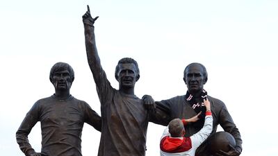 A football fan ties a scarf around a statue of Manchester United and England star Bobby Charlton outside the club's Old Trafford stadium after his death at the age of 86. Reuters
