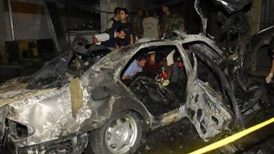 Lebanese investigators, inspect the damaged car of Sheik Saleh Aridi who was killed by a bomb explosion.