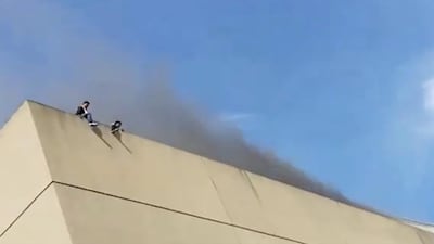 People are seen on the roof of a building as smoke rises during a fire in Davao, the Philippines, in this still image taken from a social media video on December 23, 2017. Ashley Nicole Avila Rafaela / Reuters