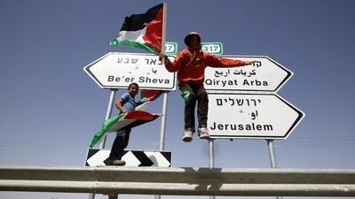 Palestinians place Palestinian flags on road signs during a protest against the confiscation of their land and annexed it for the nearby Jewish settlements of Ma'on. Abed Al Haslhamoun / EPA