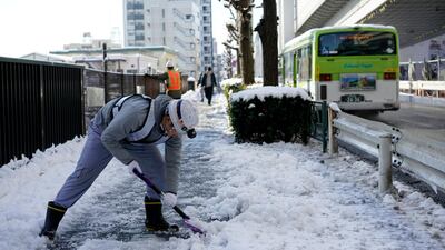 A worker clears snow from a sidewalk after snowfall in Tokyo on Tuesday. Franck Robichon / EPA