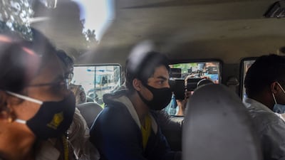 Bollywood actor Shah Rukh Khan’s son Aryan Khan, escorted by law enforcement officials, sits in a vehicle outside the Narcotics Control Bureau in Mumbai, India. AO