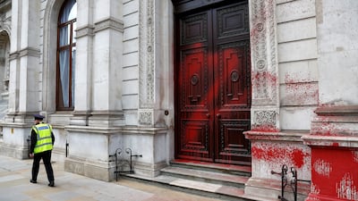 A guard walks past paint-daubed walls after a Palestine Action protest at the Foreign Office in London. Reuters