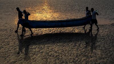 Indian fishermen from the Koli community carry a boat as they arrive after their catch near the Arabian Sea coast in Mumbai. Divyakant Solanki / EPA