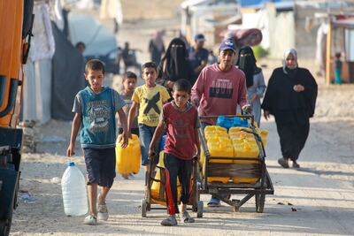 Palestinians transport water containers in a displacement camp in the Al Mawasi area in Khan Yunis in southern Gaza. AFP