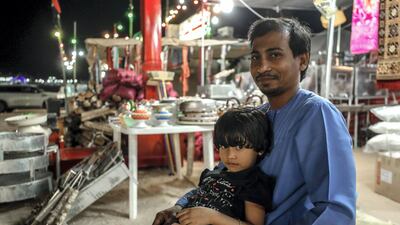 Akbar Hussein with his daughter, Muntaha, 5, tends Al Mansoori Supply general store on Millions Street at the Al Dhafra Festival. Victor Besa / The National