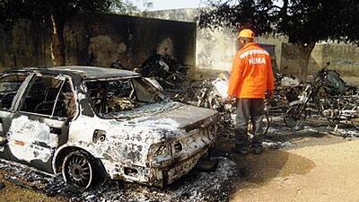 A rescue worker inspects a burnt-out car destroyed in Friday’s bomb attacks on Kano.
