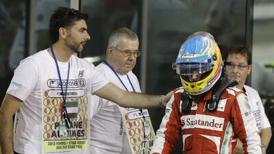 Ferrari driver Fernando Alonso of Spain is comforted by an unidentified man after a disappointing fifth-place finish in the Etihad Airways Abu Dhabi Grand Prix. Luca Bruno / AP Photo