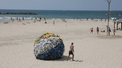 An art installation created by Tal Tenne Czaczkes of a large beach ball made of plastic waste, on display at Gordon beach in Tel Aviv, Israel. EPA