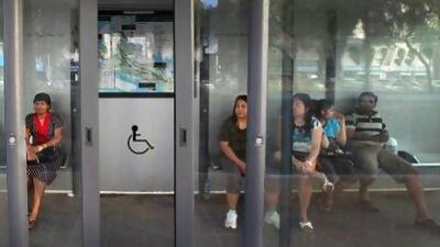 Commuters waiting for buses inside a sheltered bus stop in Abu Dhabi.
