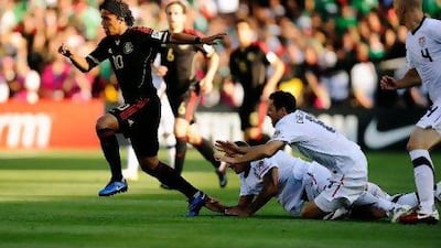 Giovanni Dos Santos of Mexico escapes from his defenders Jermaine Jones (13) and Steve Cherundolo of the United States.