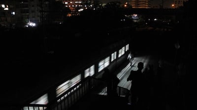 People walk along the platform using light from the train at the Maadi metro station during an electricity outage.