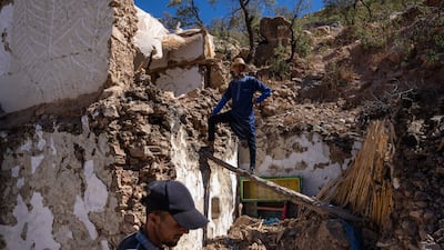 Men work to salvage goods from the ruins of their house in Douzrou. Getty Images
