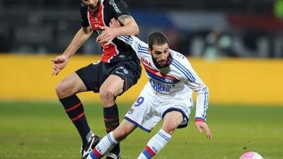 Lyon's forward Lisandro Lopez, right, fights for the ball with PSG' midfielder Thiago Motta.