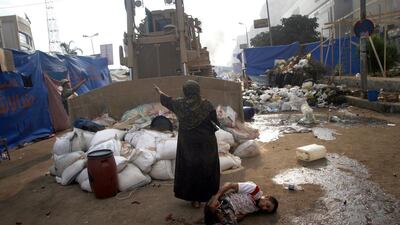An Egyptian woman tries to stop a military bulldozer from hurting a wounded youth as Egyptian security forces moved in to disperse supporters of Egypt's deposed president Mohammed Morsi. Mohammed Abdel Moneim / AFP