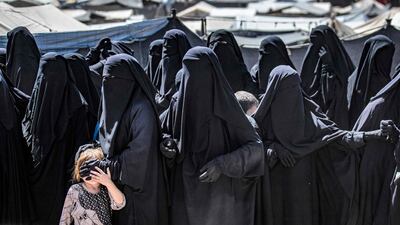 Women and a child queue to receive humanitarian aid packages at the Kurdish-run Al Hol camp in Syria's Hasakeh governorate in 2021. AFP