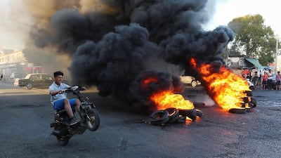 A young man boy rides his motorbike near burning tires during a sit-in protest against the fall in pound currency and mounting economic hardship, in Ghazieh. Reuters