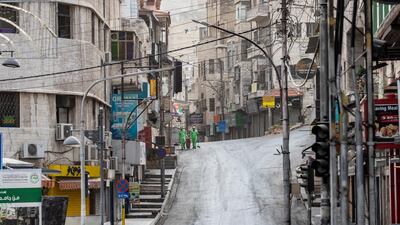 Jordanian workers clean the street during the lockdown in Amman. EPA