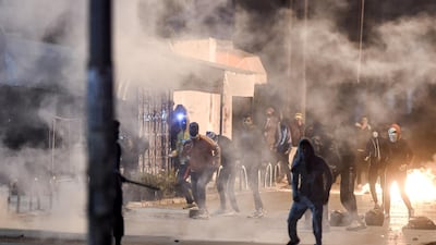 Protesters stand amidst fumes as they block a street during clashes with security forces in the Ettadhamen city suburb on the northwestwern outskirts of Tunisia's capital Tunis amidst a wave of nightly protests in the North African country. AFP