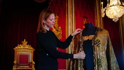 Caroline de Guitaut, deputy surveyor of the king's works of art at the Royal Collection Trust, adjusts the Imperial Mantle