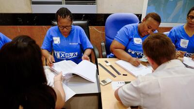 International Electoral Commission employees check foreign-registered South African citizens’ names against the voters’ roll before letting them cast their vote in the country’s general election. Antonie Robertson / The National