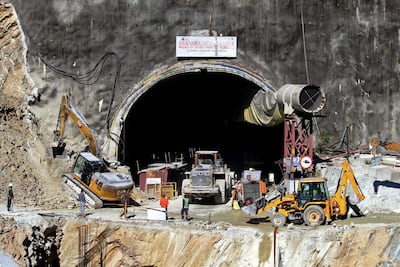 Rescue workers stand at an entrance of the under construction road tunnel, days after it collapsed. AFP