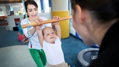 Samantha Ruppert, centre, swings with help from her mum, Stephanie Kinnick, right, and Bianca Belghith, left, at My First Gym. Delores Johnson / The National