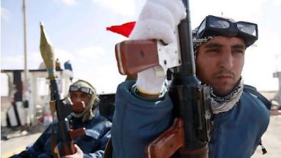 Rebel fighters hold rocket-propelled grenades as they drive through a checkpoint west of Ajdabiyah yesterday.