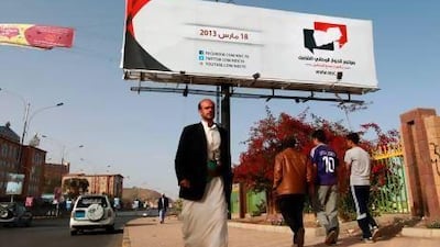 Yemenis walk under a billboard advertising their country’s UN-backed national dialogue conference in Sanaa.