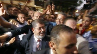 Egypt's Muslim Brotherhood candidate Mohammed Morsi, centre, walks among jubilant supporters after the announcement of presidential election results at the Cairo electoral headquarters yesterday.