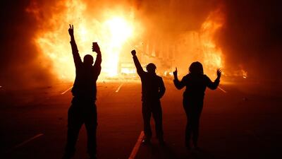 Protesters gesture in front of a burning auto parts store in Ferguson, Missouri. Tannen Maury / EPA