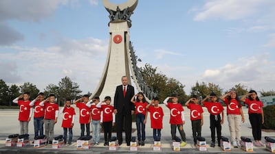 Turkish President Recep Tayyip Erdogan poses for photos with primary school students from a village of Black Sea city of Samsun, who give a military salute outside the presidential palace, in Ankara. Erdogan has responded angrily to widespread criticism in the West of Turkey's incursion in northeast Syria. AP, Pool