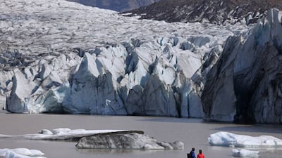 Visitors at the base of the melting Svinafellsjokull glacier, as ice chunks fallen from the glacier float in a lake of meltwater on August 13, 2021. Svinafellsjokull is one of dozens of glacier tongues that descend from Vatnajokull, Iceland's biggest ice cap. Getty