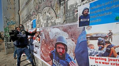 Palestinian journalists put up posters showing their wounded colleague Muath Amarneh during a protest in Bethlehem. Reuters