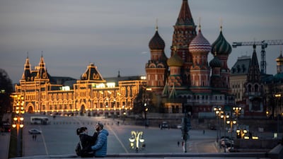 A couple enjoy warm weather on a bridge with St. Basil's Cathedral, right, and an almost empty Red Square after sunset in Moscow, Russia. AP Photo