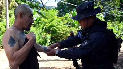 A police officer checks a man with tattoos during an operation to find gang members in Santa Ana. AFP
