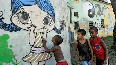 Children play next to a graffiti of street art in Havana, on July 12, 2017. / AFP PHOTO / YAMIL LAGE