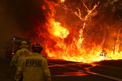 Firefighters rush to move their vehicle as a wildfire threatens the road on the outskirts of Bilpin in Sydney, Australia, in 2019. Getty Images