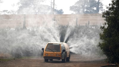 Property owners use a commercial watering machine to hose down their property as the Grose Valley Fire approaches Bilpin, Australia. Reuters