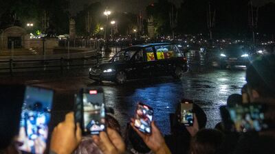 People take photos as the hearse arrives at Buckingham Palace. Reuters