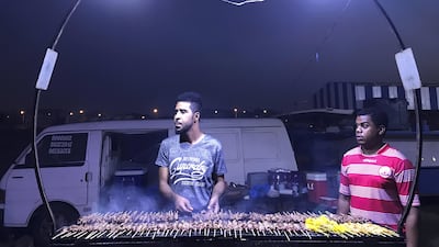 Suleiman Essam, 28, right, and Abdulla Masoud, 27, prepare mashakik skewers for motorists in Seeb, Oman. Anna Zacharias / The National
