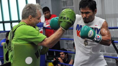 Manny Pacquiao, right, hits the pads with trainer Freddie Roach. Roach is supremely confident his man will end Floyd Mayweather's unbeaten record. Ted Aljibe / AFP