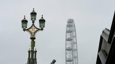 A man wearing a face mask walks over Westminster Bridge on a rainy day in central London. AP Photo