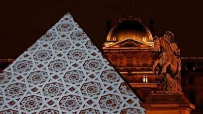 The dome pattern of the Louvre Abu Dhabi is projected onto the Louvre Pyramid in Paris on Wednesday night. Christian Hartmann / Reuters