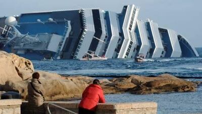 People look on at the cruise liner Costa Concordia aground in front of the harbour of the Isola del Giglio (Giglio island) after hitting underwater rocks on January 13. Italian rescuers resumed their search on board a crashed cruise ship the same day, as salvage workers prepared to pump out fuel from its tanks to avoid an environmental disaster.