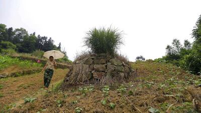 A woman walks past a tomb at Heshan village in Shimen county. Jason Lee / Reuters