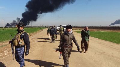 Members of the Kurdish peshmerga forces and the Iraqi security forces patrol on a road as smoke billows from the Khubbaz oil field, some 25 km west of the northern city of Kirkuk, on February 2, 2015, a fews days after Peshmerga forces and police retook the area from ISIL. Peshmerga forces are struggling to hang on to gains they have been making against the militants. Marwan Ibrahim/AFP Photo