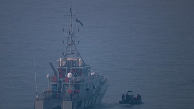 A UK Border Force vessel sails in front of a boat carrying migrants. Getty