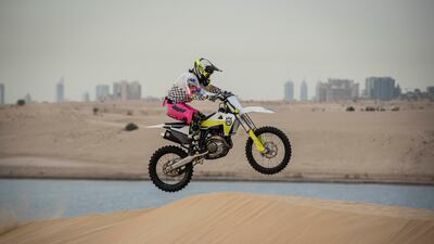 Michelle Christie gets air on a dune, with the buildings of Dubai in the background