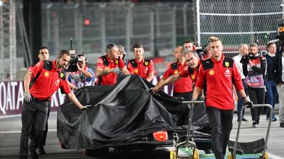 Ferrari crew return Carlos Sainz's car to the garage after it was damaged during first practice. AFP